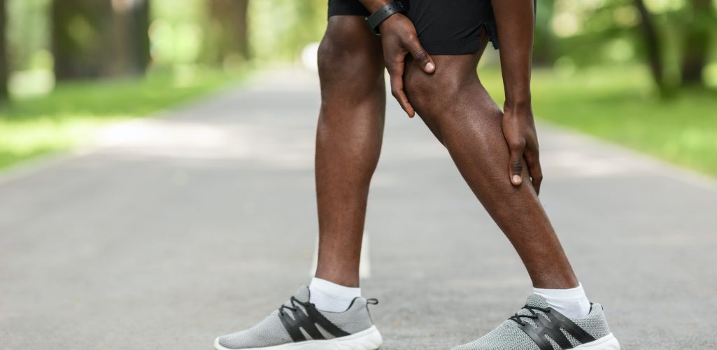 African guy rubbing his aching leg, got cramp while jogging